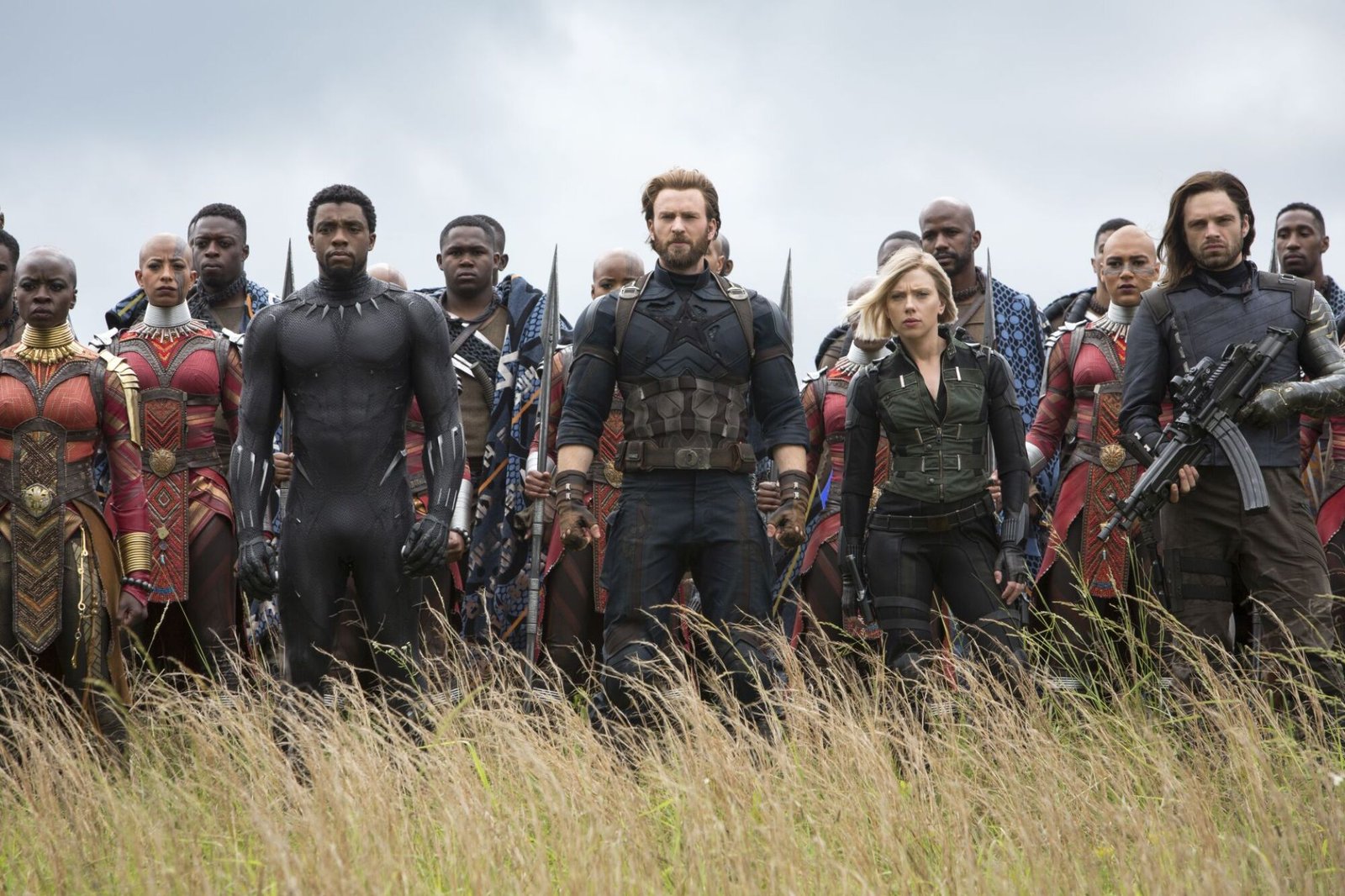 images-477-fill_-size_2000x1333-v1631049911 Wide shot of Captain America (Steve Rogers) in a dark, rugged super soldier suit, leading battle forces including soldiers from Wakanda, Bucky Barnes, and Black Widow. They assemble in a field, awaiting an attack.