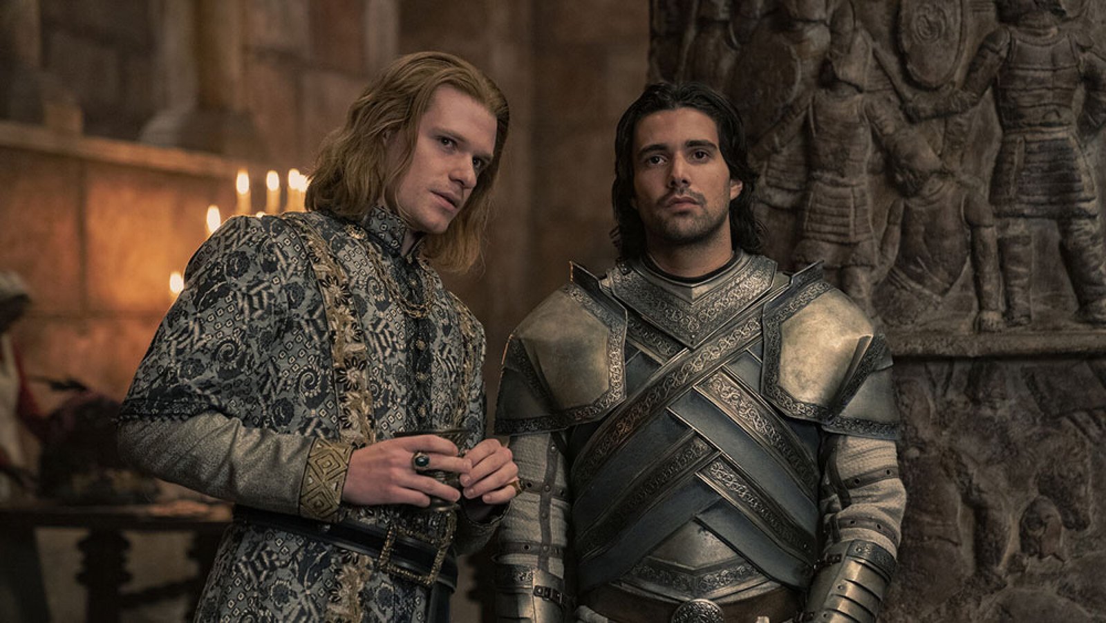 images-5-fill_-size_2000x1126-v1715267481 Two men, one in robes and one in armour, talk in a hall.